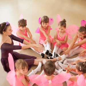 a dance teacher and little girls sitting on the floor